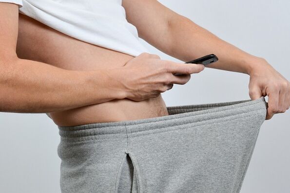 男性がズボンを下ろして肥大したペニスを見つめる